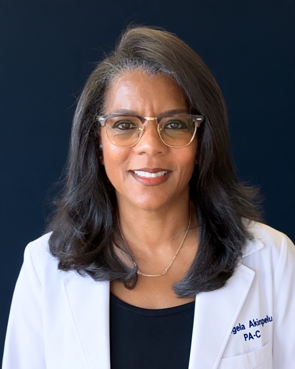 Angela Akinpelu, PA-C, smiling, in glasses and a white coat